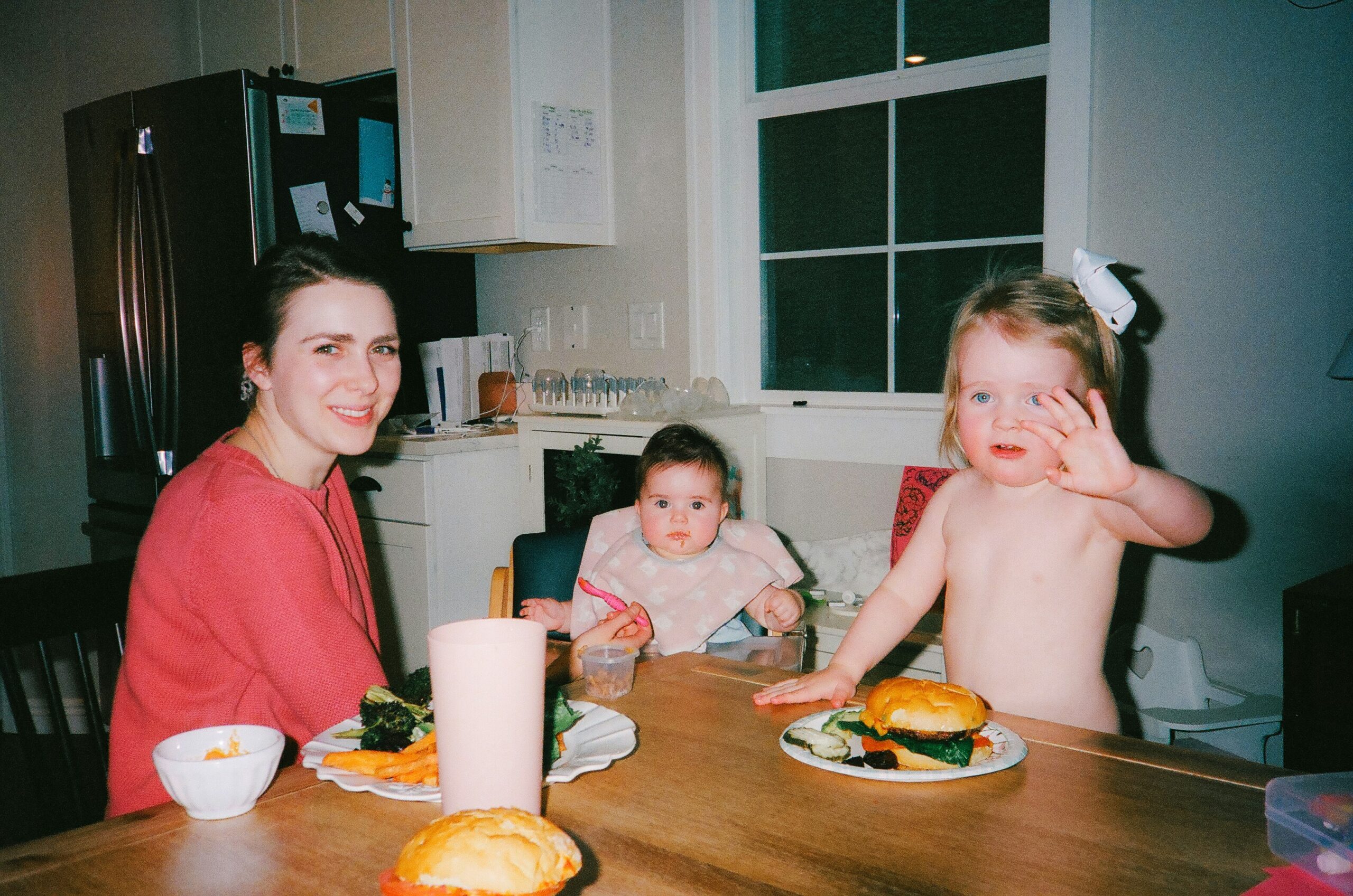 a couple of kids sitting at a table with plates of food