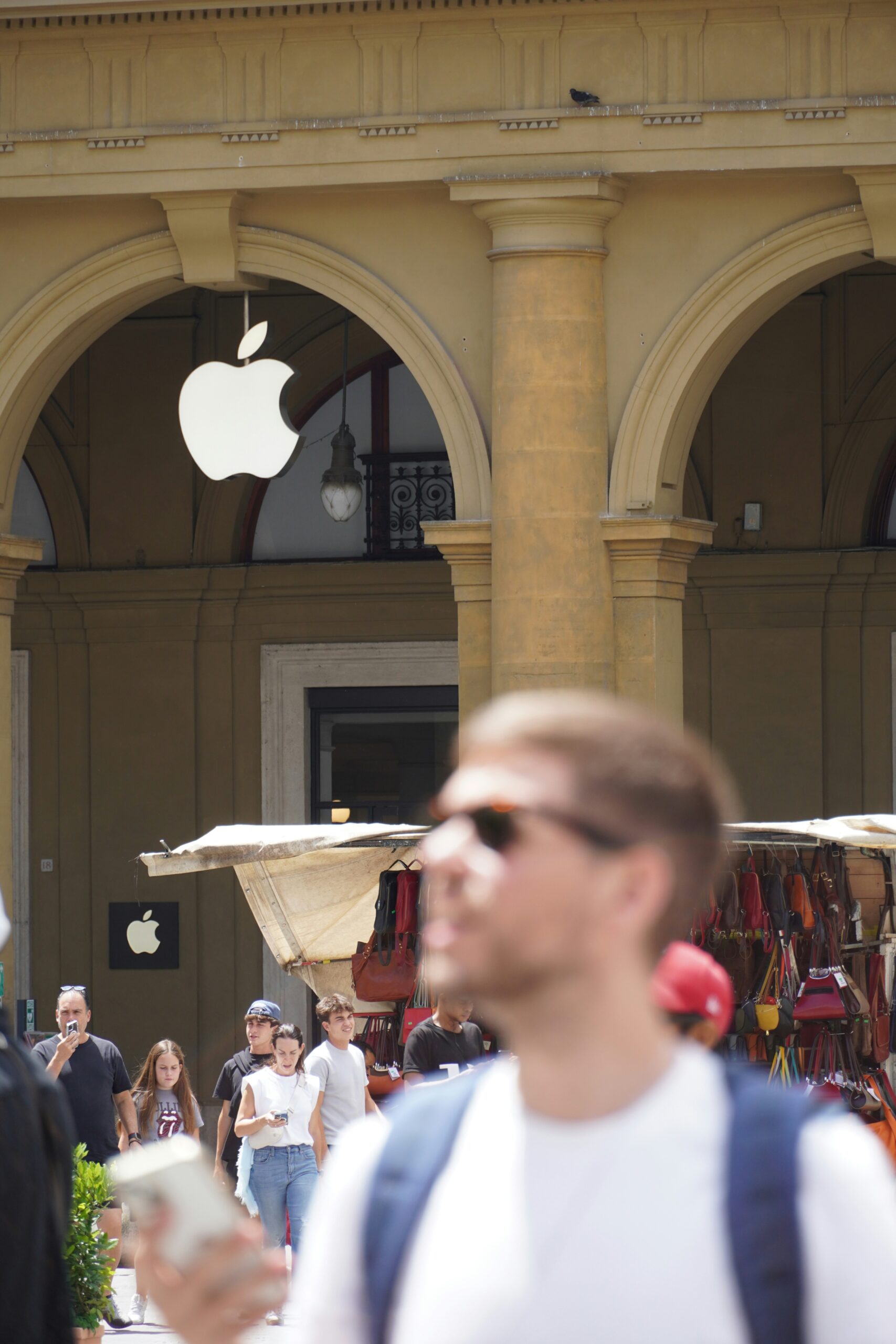 A group of people walking down a street next to an apple store