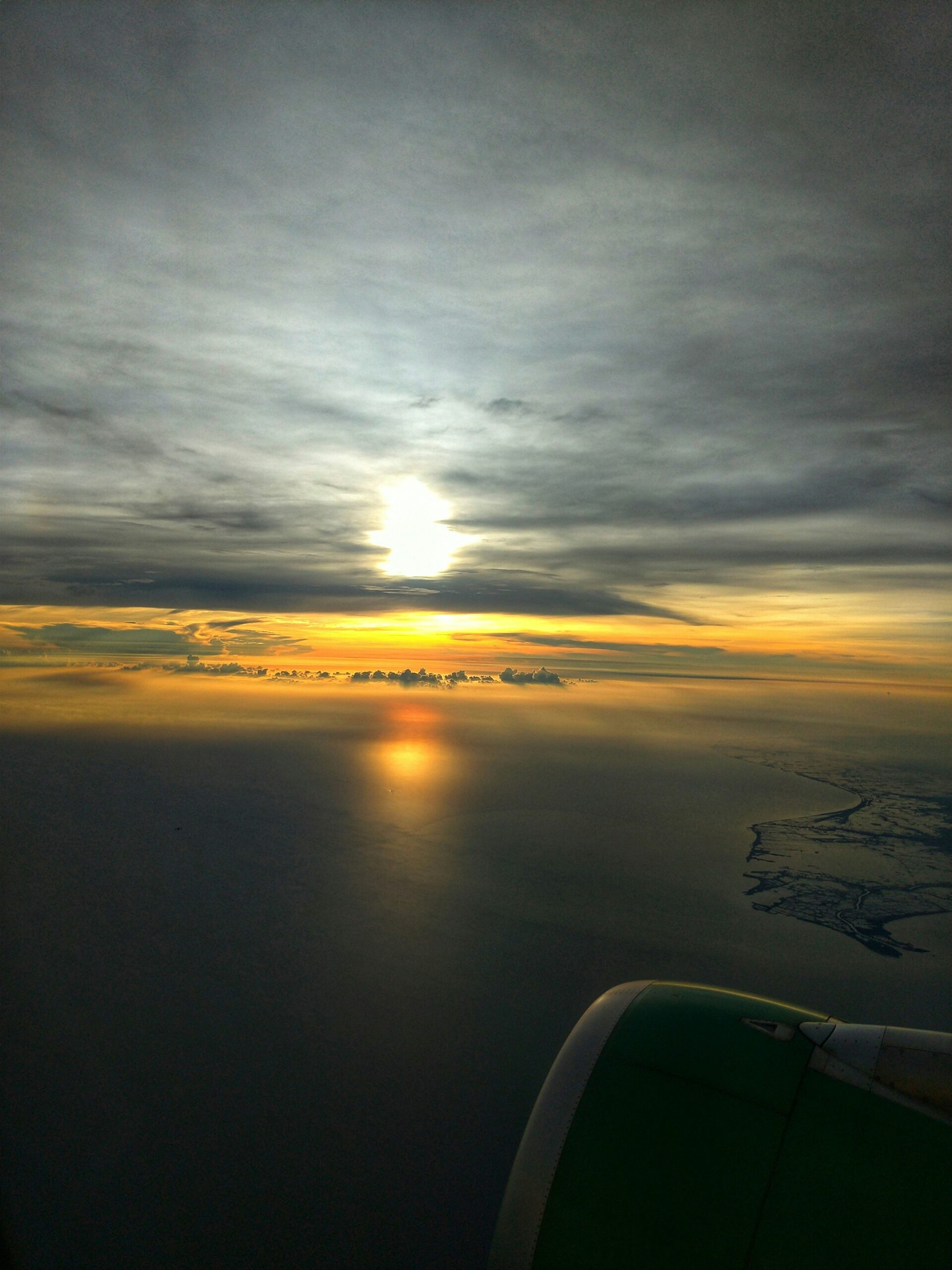 the sun is setting over the ocean as seen from an airplane